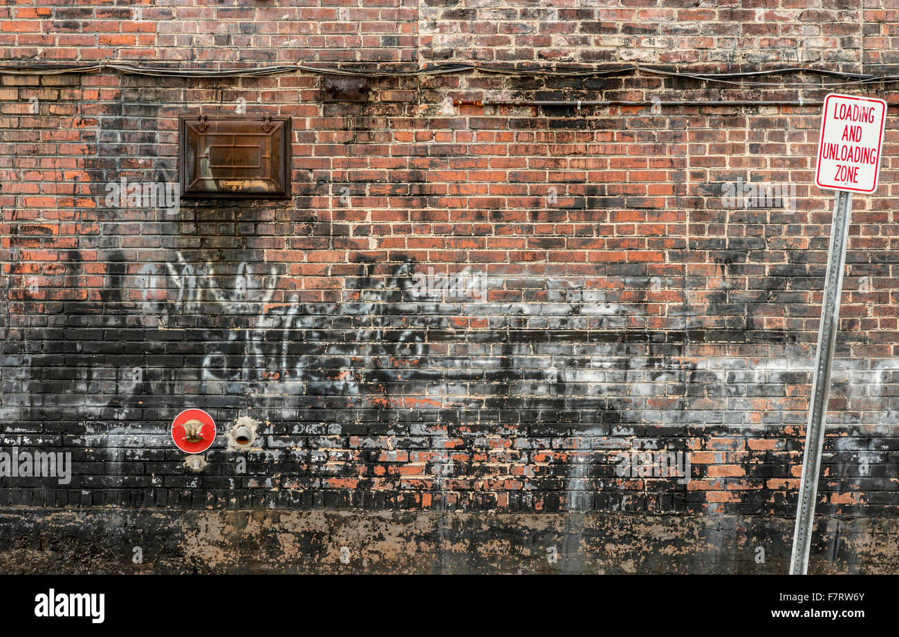 Cluttered Old Brick Wall Background with Graffiti and Sign Stock Photo