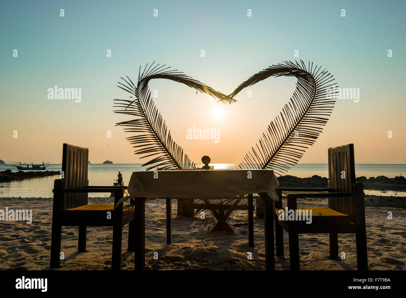 Table on the beach with a heart made of palm fronds, sunset, Koh Samui island, Gulf of Thailand, Thailand Stock Photo