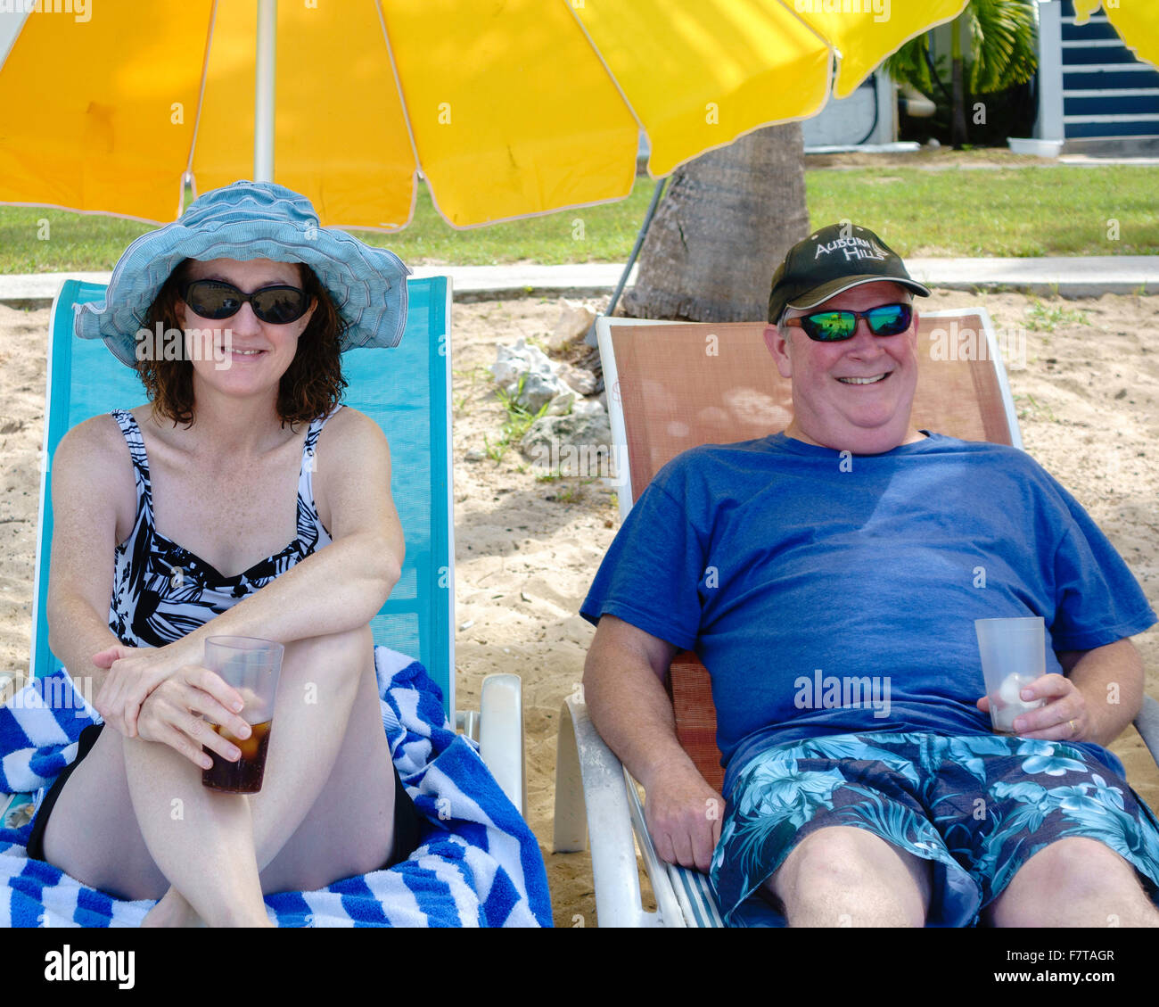 A 50 Year Old Caucasian Couple Relaxing In Beach Chairs Under Umbrellas