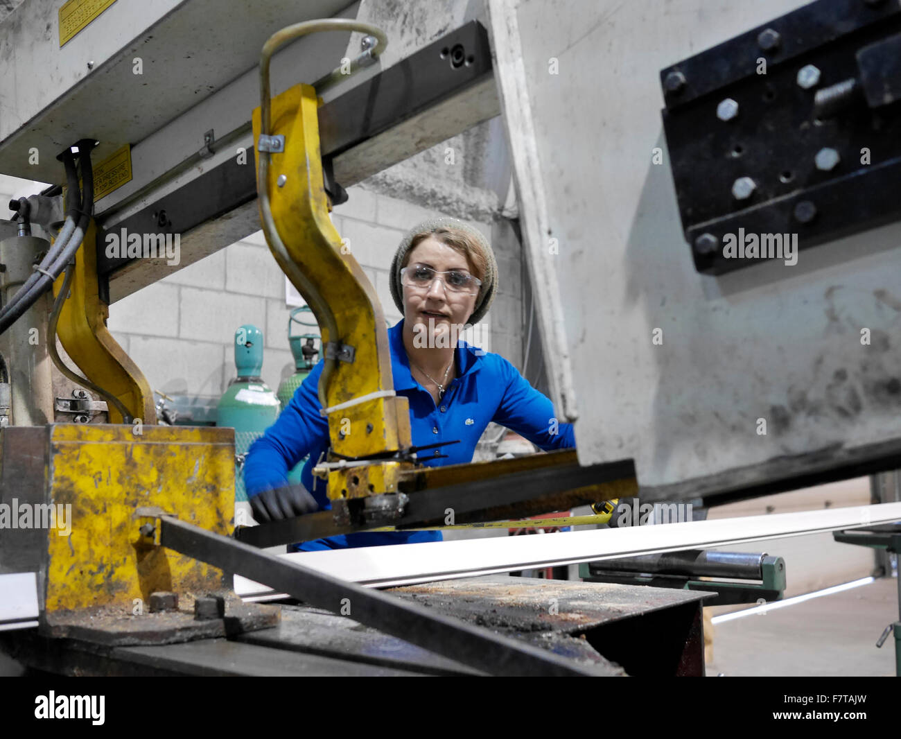 Female worker fine tuning machine for cutting a metal angle. Stock Photo
