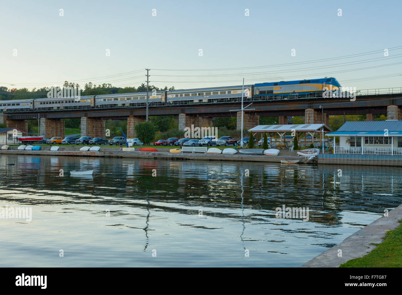 A Via Rail train passes by along a bridge behind the Port Hope Harbour. Port Hope, Ontario, Canada. Stock Photo