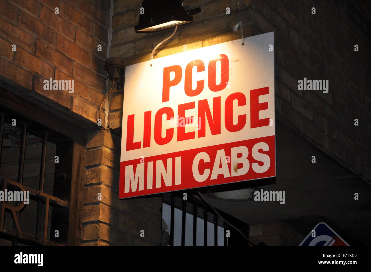 A brightly lit mini cab service sign in London at night Stock Photo