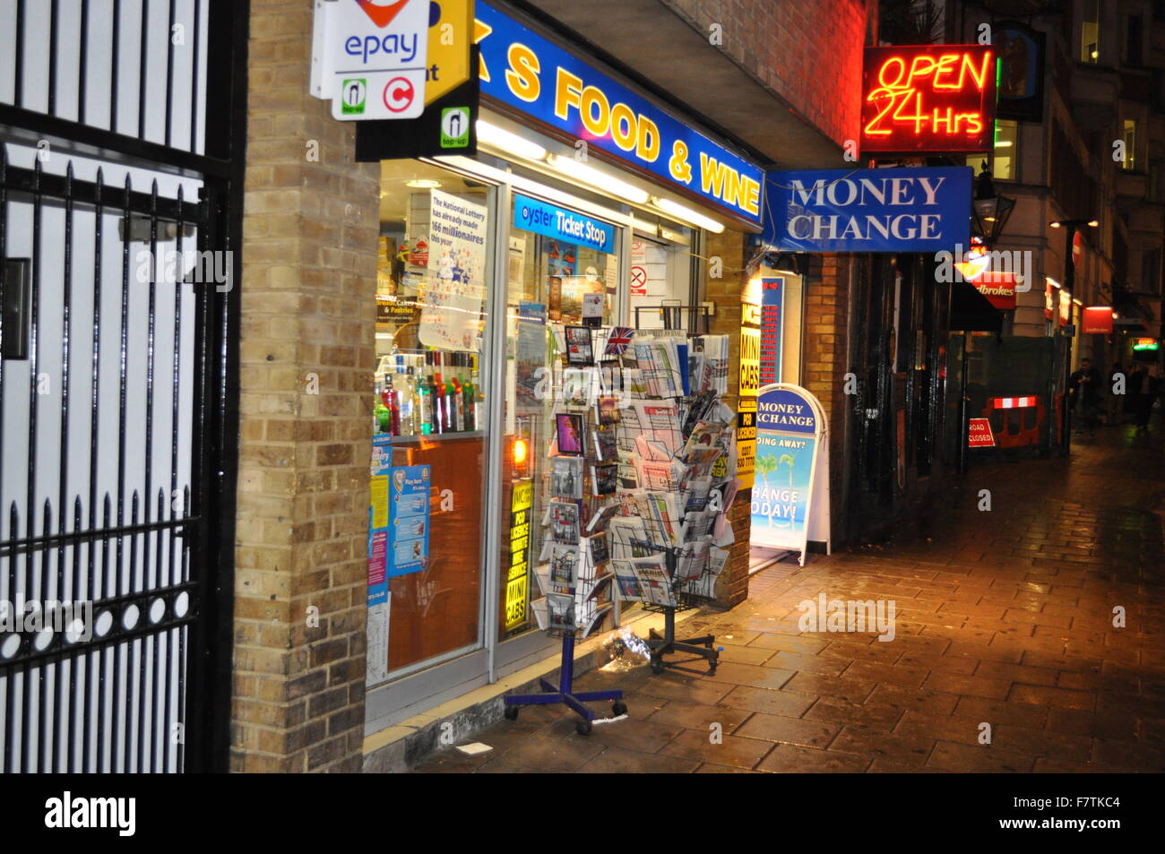 A strip of shops including an off license at night time Stock Photo