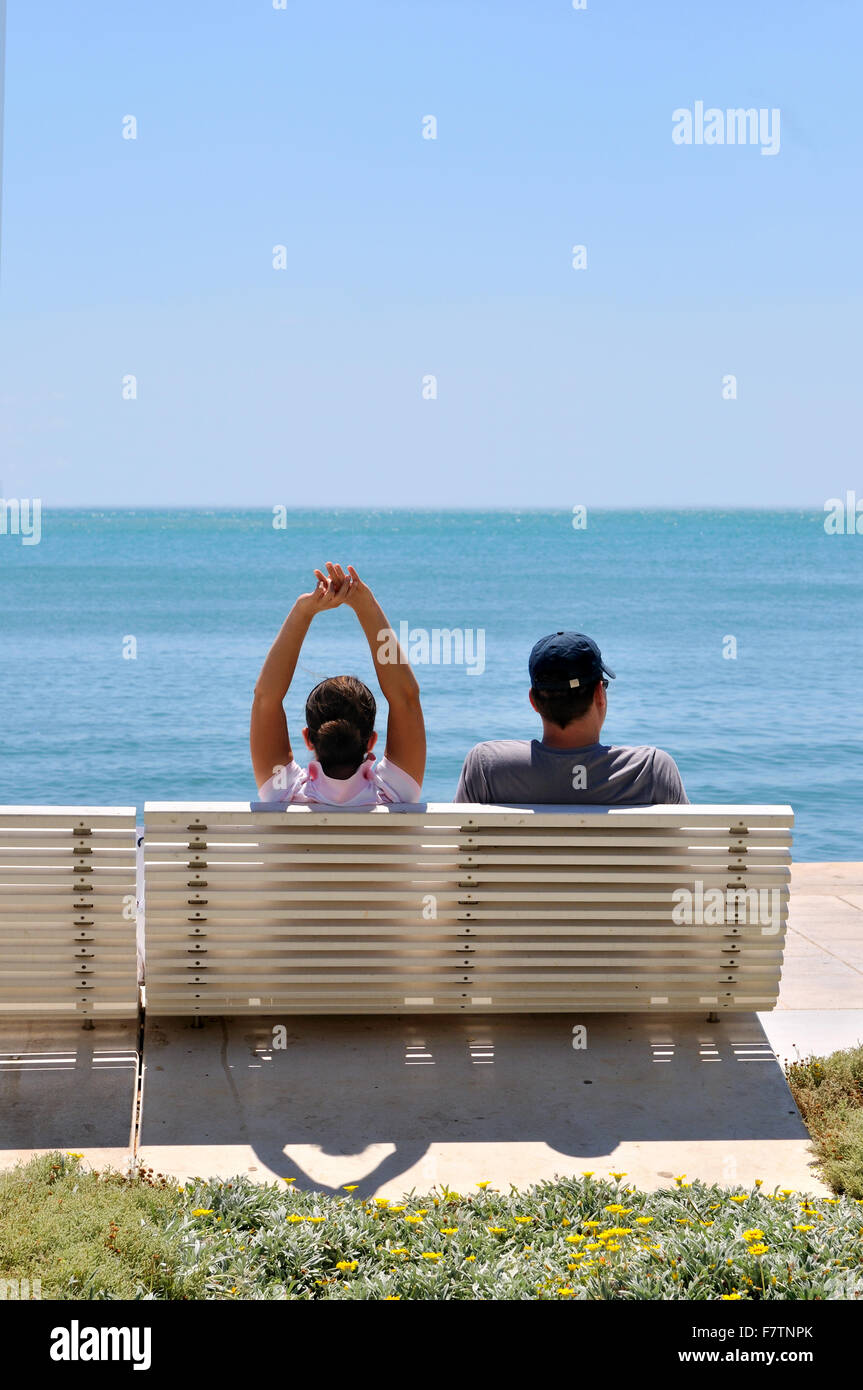 Happy young couple sitting on the beach relaxing Stock Photo - Alamy