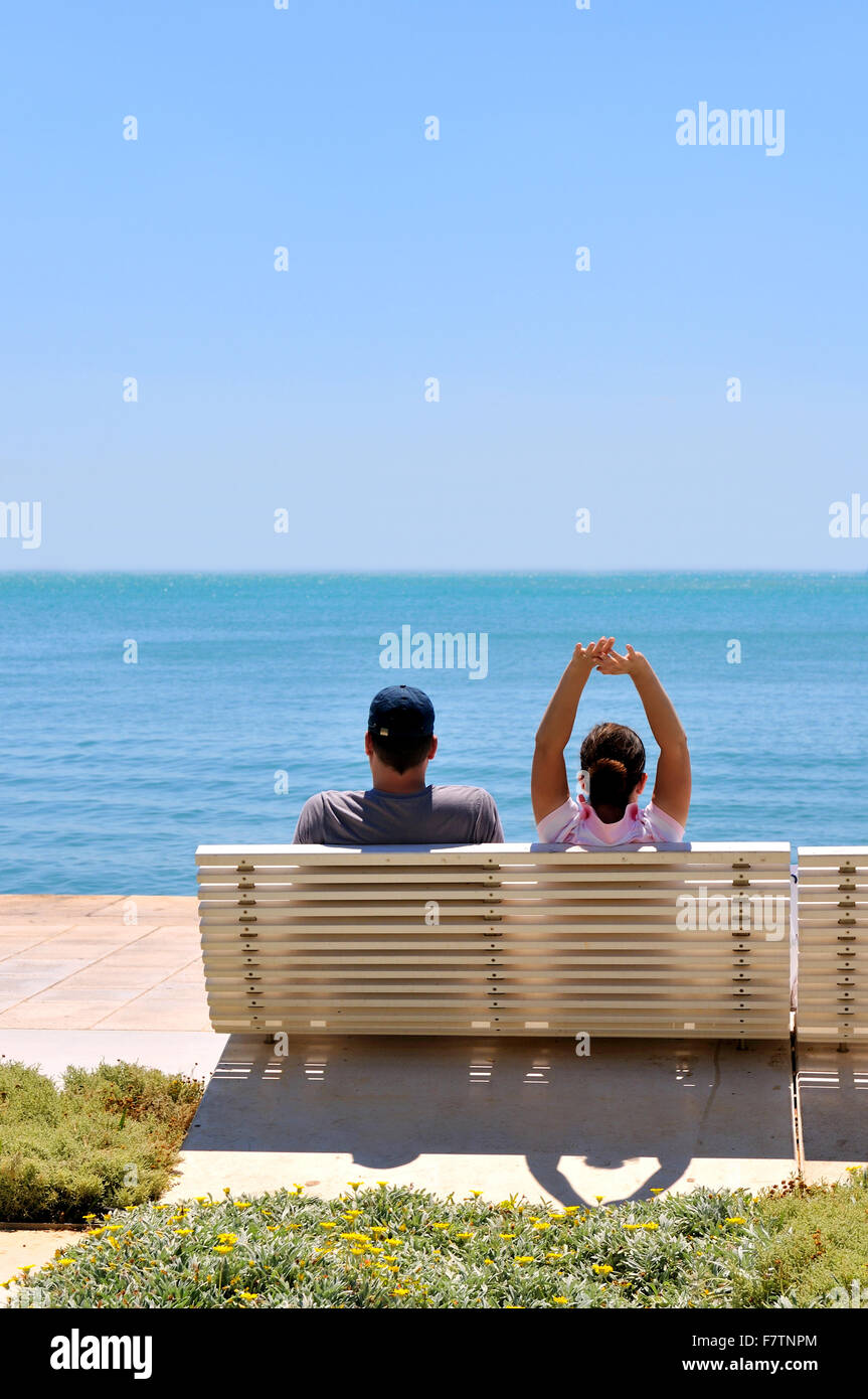 Happy young couple sitting on the beach relaxing Stock Photo - Alamy