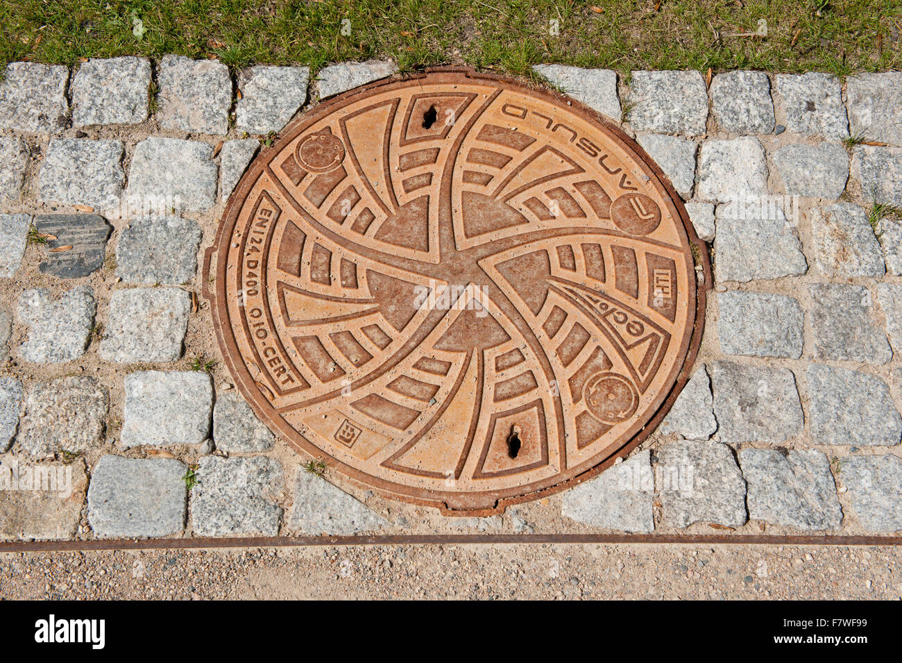 Decorative brown manhole cover of sewage well by Fansuld in park Lazienki Krolewskie w Warszawie, Royal Baths Park, Warsaw... Stock Photo