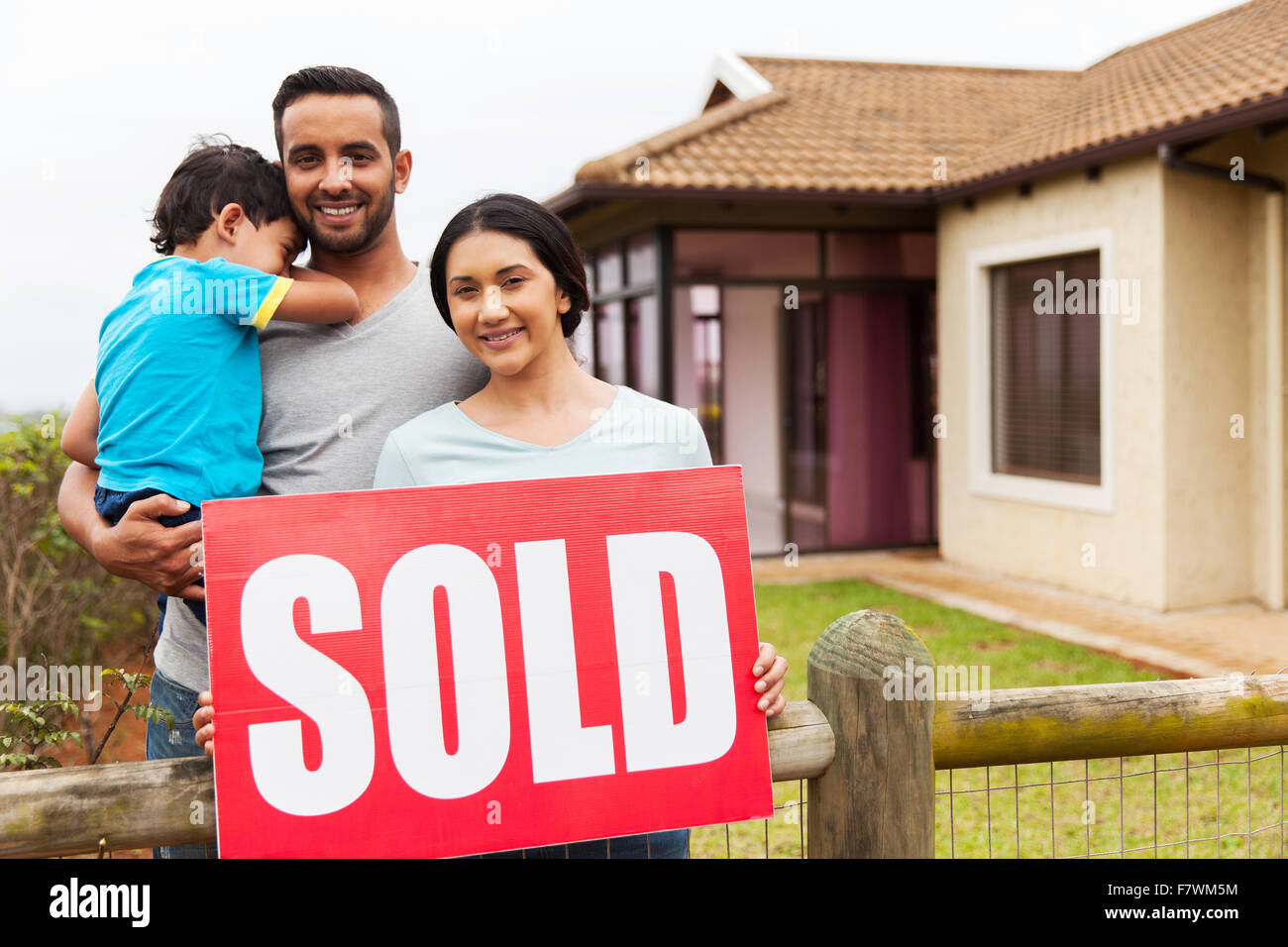 Indian family standing outside their house and holding sold sign Stock ...