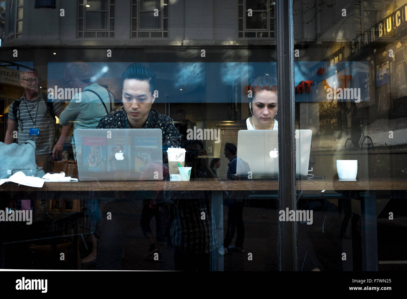 Young man and woman using Apple Mac computer in a cafe, Birmingham, UK