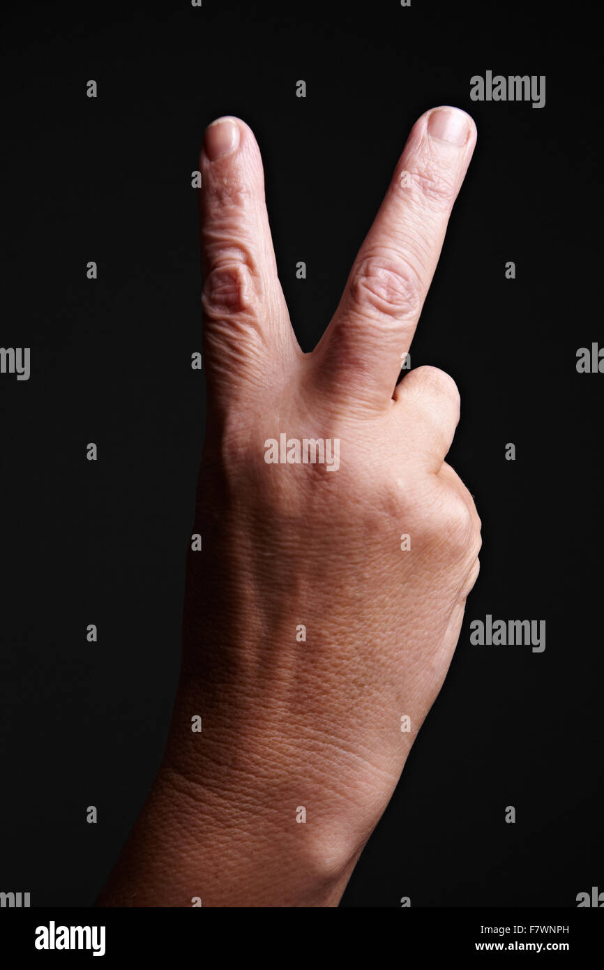 Old hand with wrinkles showing victory sign Stock Photo
