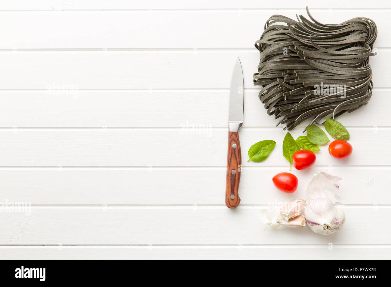 noodles, garlic, tomatoes and basil leaves on white table Stock Photo ...