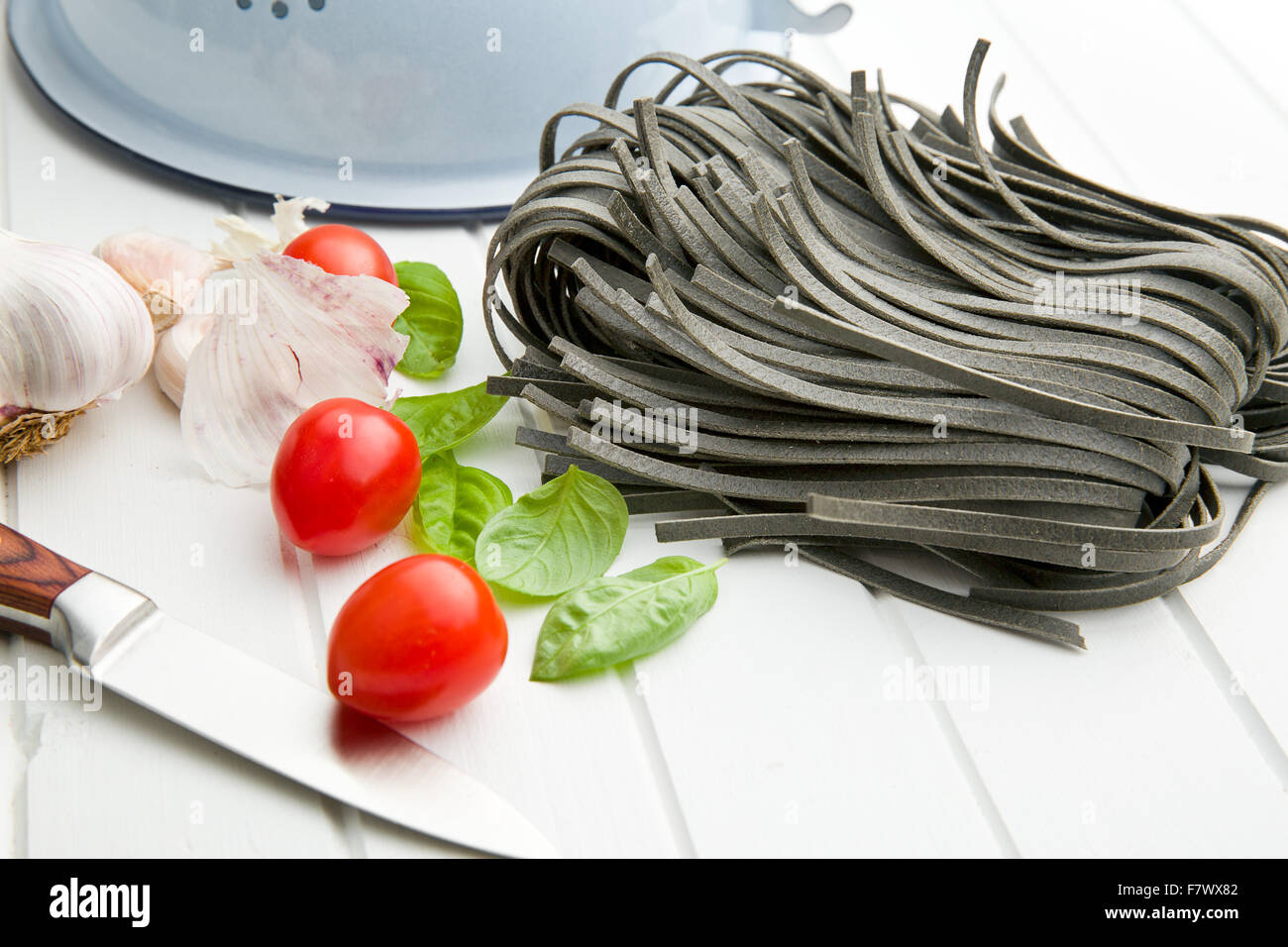 noodles, garlic, tomatoes and basil leaves on white table Stock Photo ...