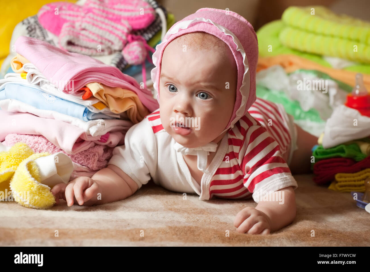 Baby Girl With Stacked Of Children s Clothes Stock Photo Alamy