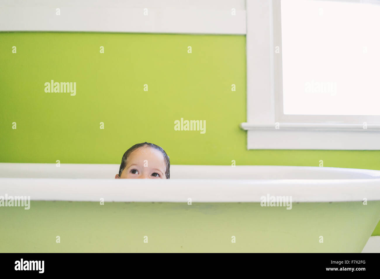 Girl looking over edge of a bath Stock Photo - Alamy