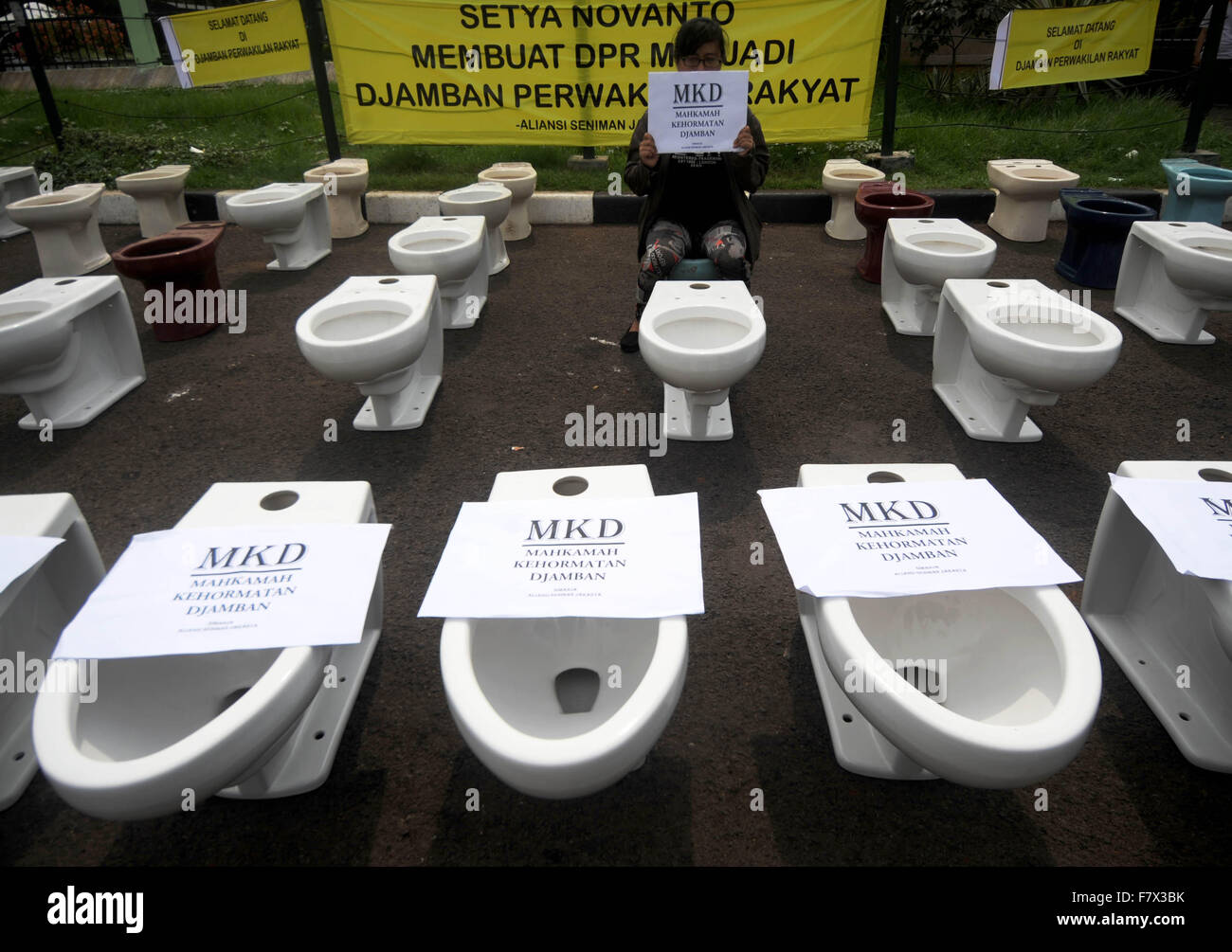 Jakarta. 3rd Dec, 2015. A woman sits on a water closet displayed during a protest in front of the House of Representative building in Jakarta, Indonesia. Dec. 3, 2015. An Indonesian minister testified against the House of Representative's speaker Wednesday, accusing him of trying to convince the regional director of a mining giant that its license could be extended in exchange for shares. © Agung Kuncahya B./Xinhua/Alamy Live News Stock Photo