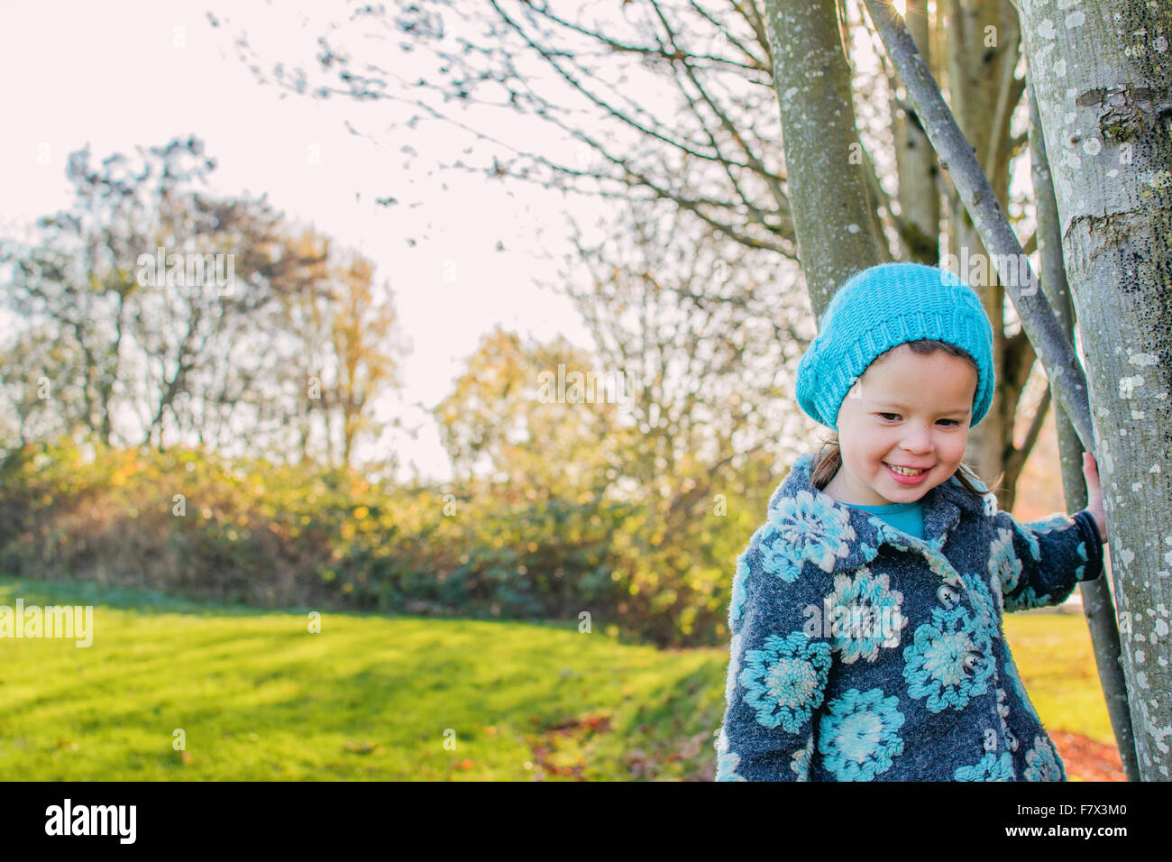 Girl standing by trees, smiling Stock Photo - Alamy