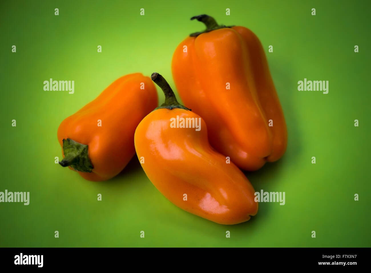 Orange bell peppers on green background Stock Photo