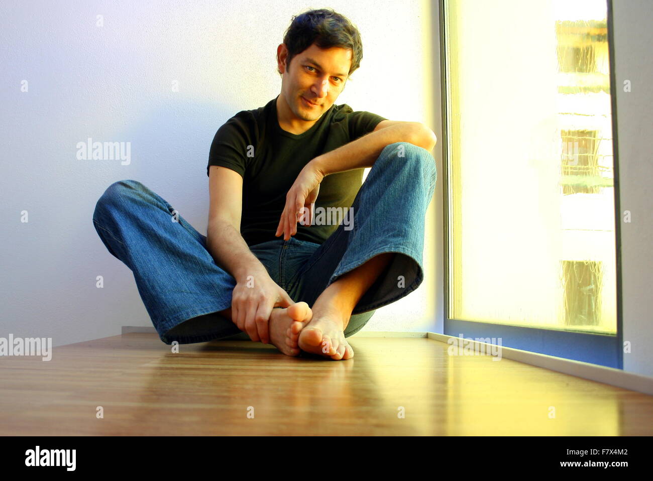 Smiling man sitting on floor Stock Photo - Alamy