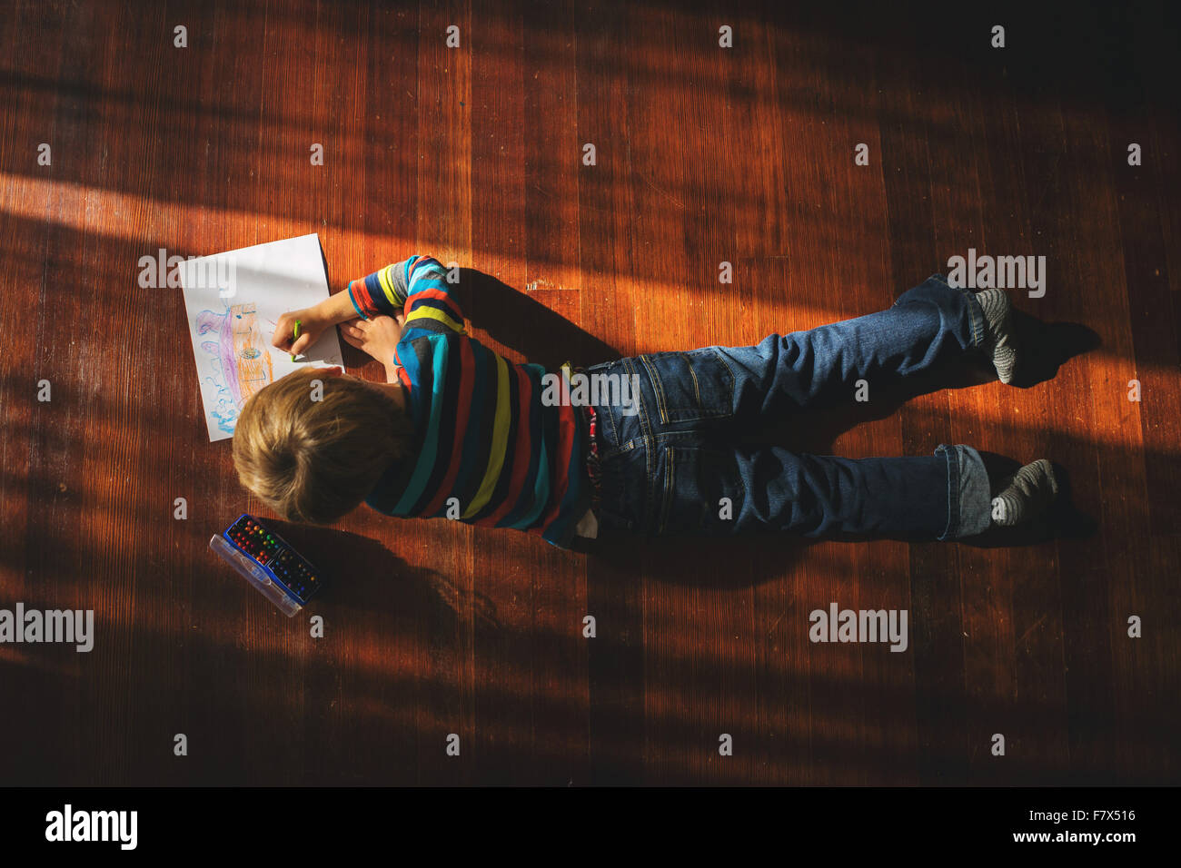 Overhead view of a boy lying on floor drawing a picture Stock Photo
