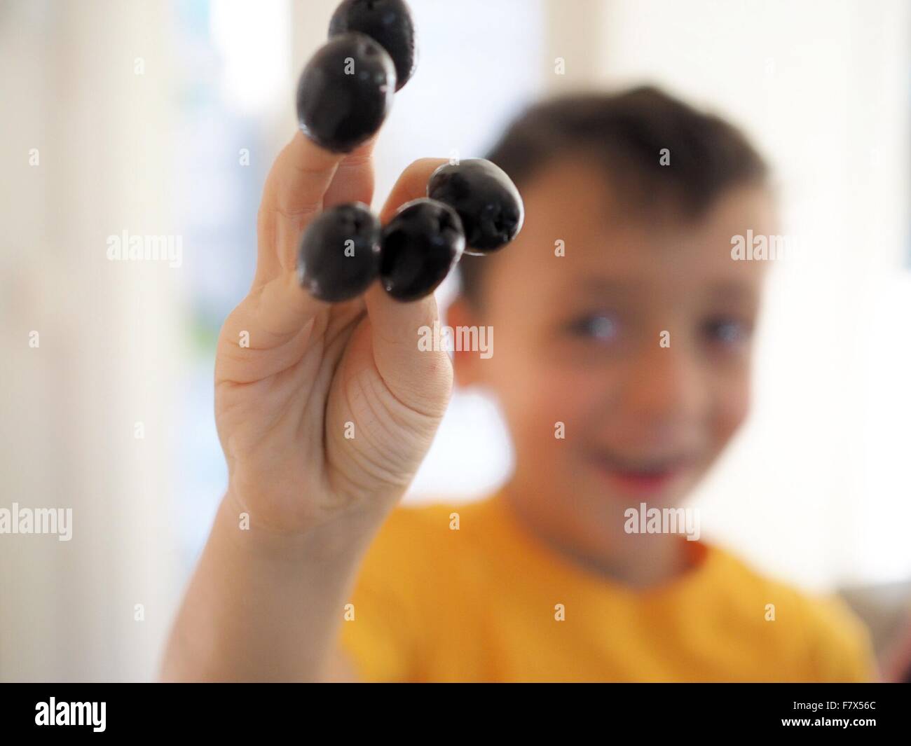 Boy with olives on his fingers Stock Photo