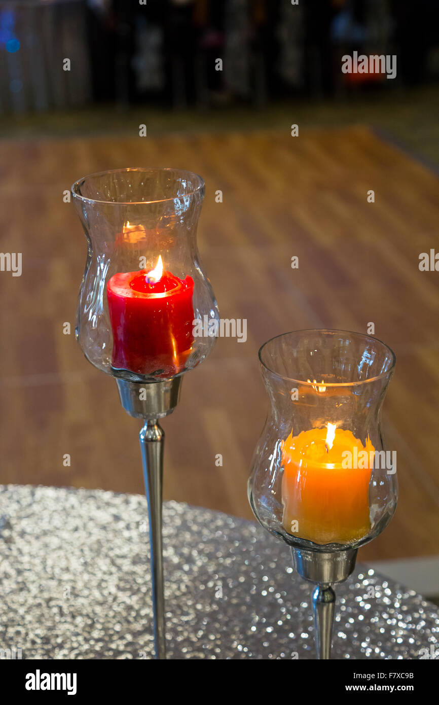 Wedding reception decor of a red candle lit and producing candlelight