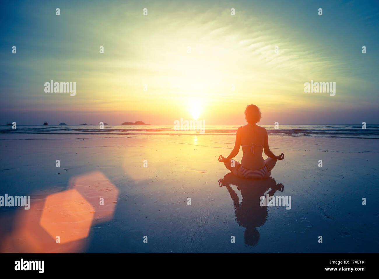 Silhouette meditation yoga woman on the background of the sea and amazing sunset. Healthy lifestyle. Stock Photo