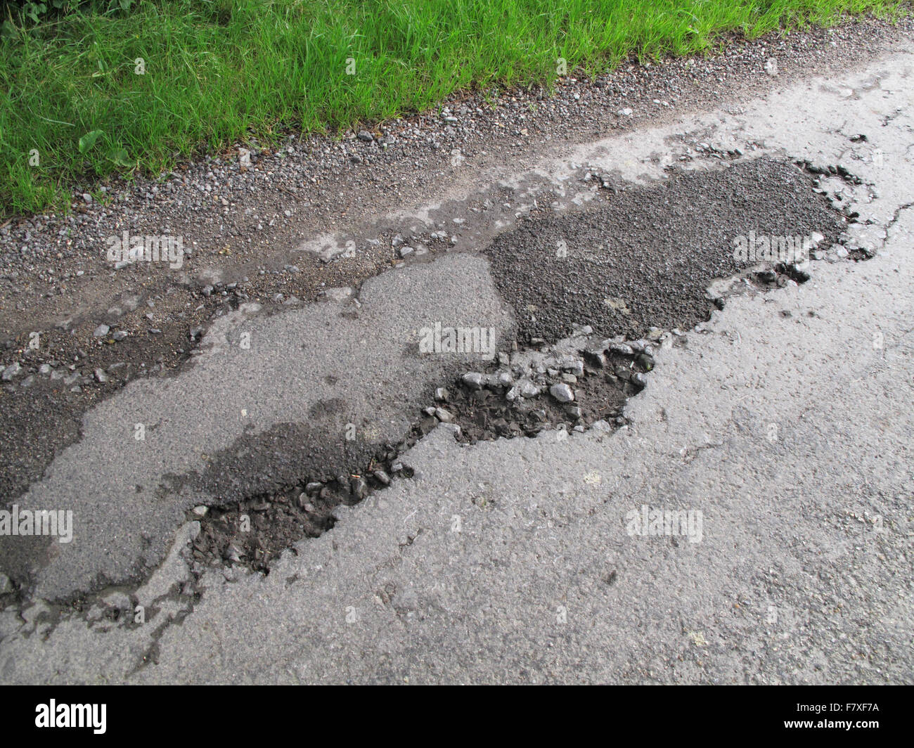 Potholes in broken tarmac country road unmarked and dangerous