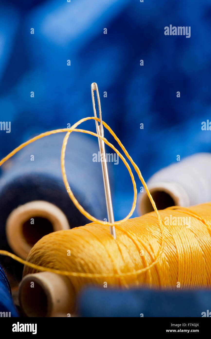 needle and yellow thread on the blue background Stock Photo Alamy