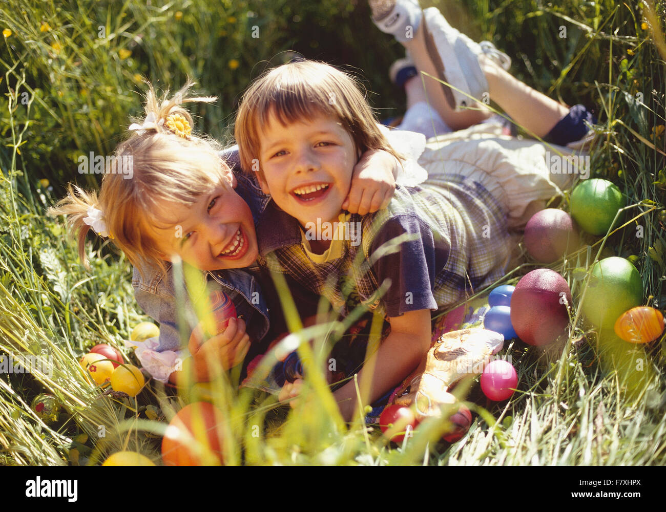 Zwei Kinder liegen mit Ostereiern in Wiese Stock Photo