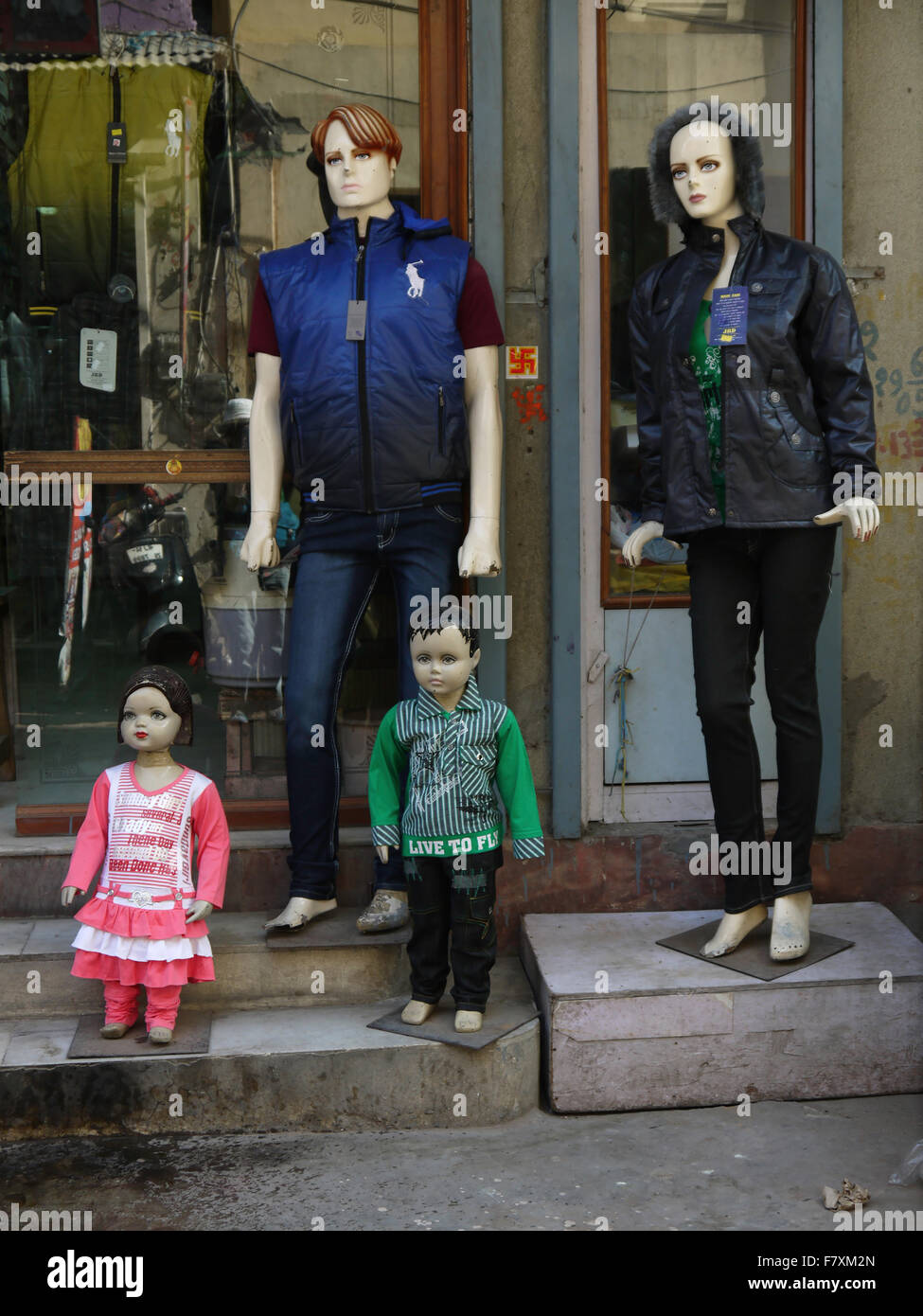 Mannequin models display outside a shop window . Two adults and two