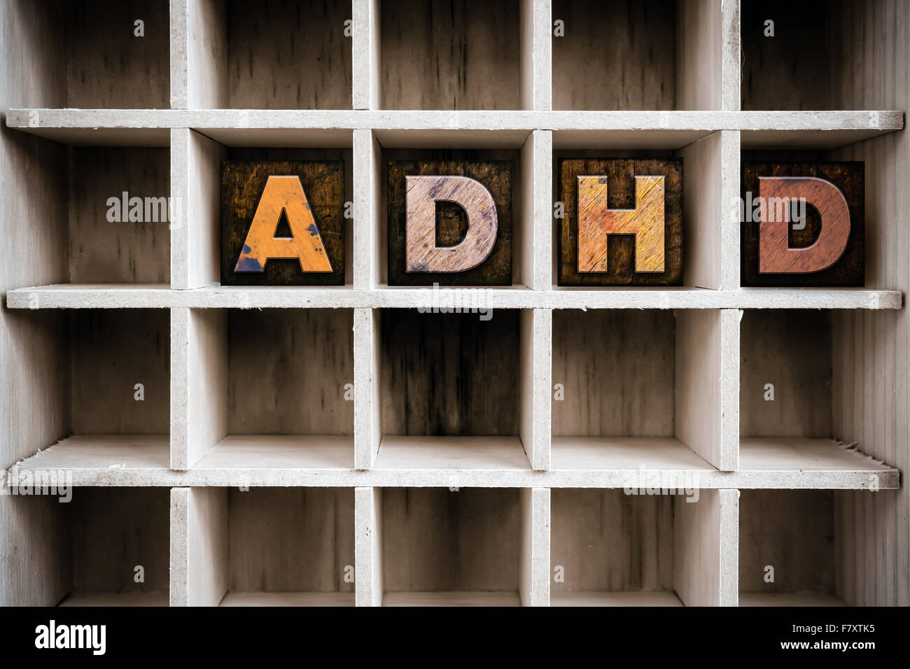 The word "ADHD" written in vintage ink stained wooden letterpress type in a partitioned printer's drawer. Stock Photo