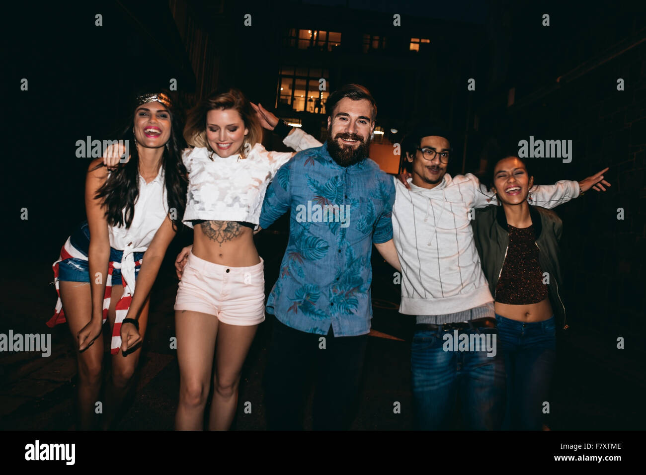 Portrait of group of friends having party together, outdoors. Multiracial young people hanging out in evening. Stock Photo