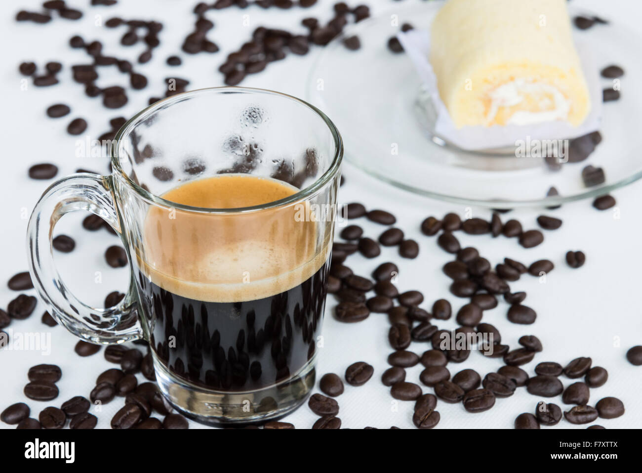 Hot espresso shot in the clear glass with soft roll cake, select  focus. Stock Photo