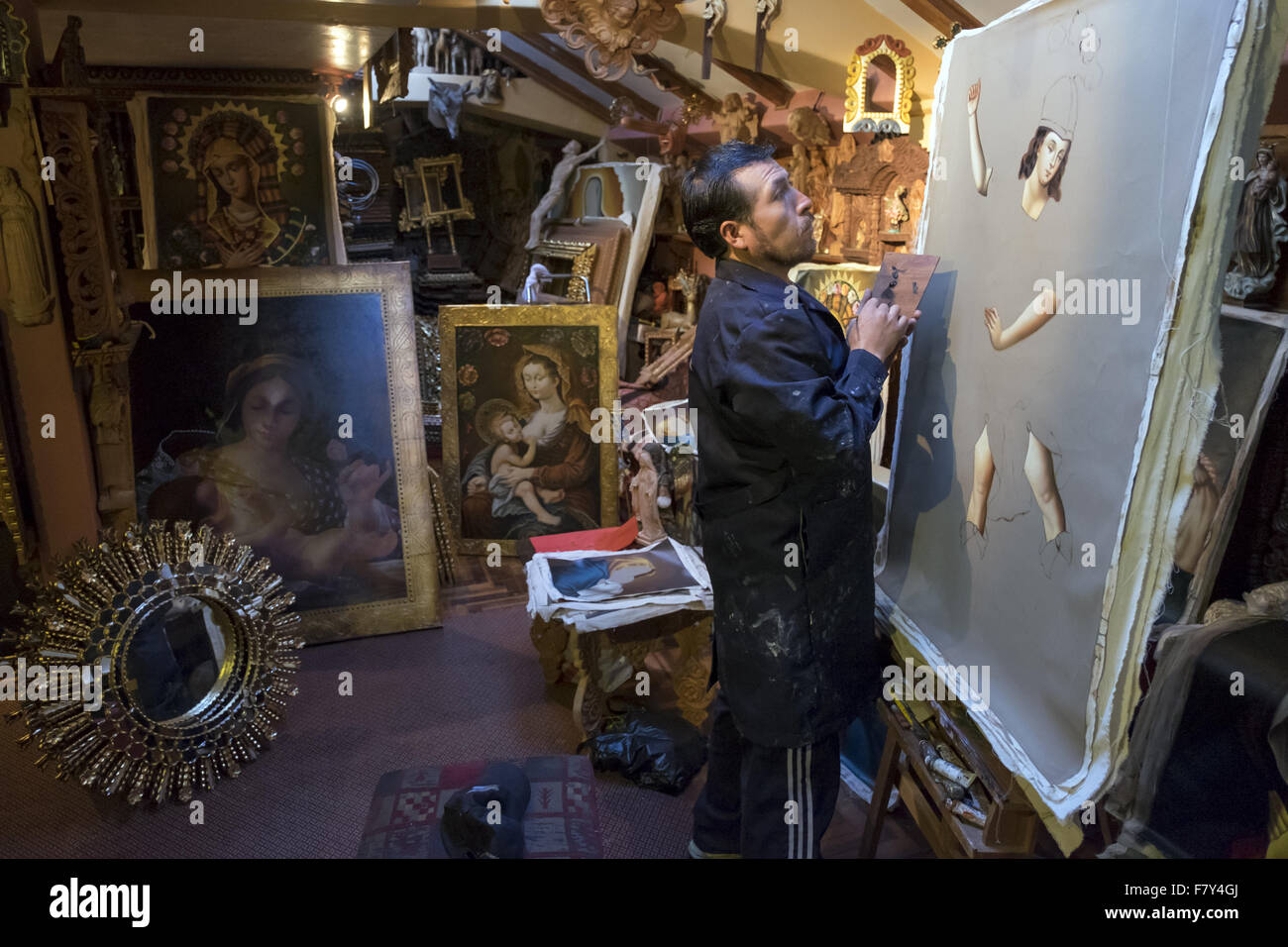 Cesar Augusto painter working in his studio with some paintings of religious subjects. Stock Photo