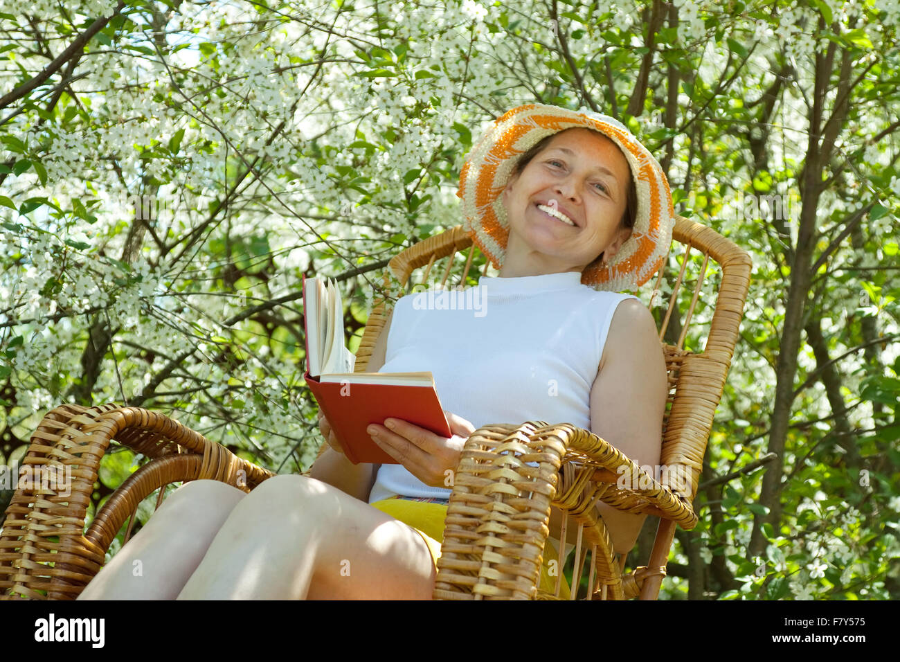 Mature woman reading book in blossoming garden Stock Photo - Alamy