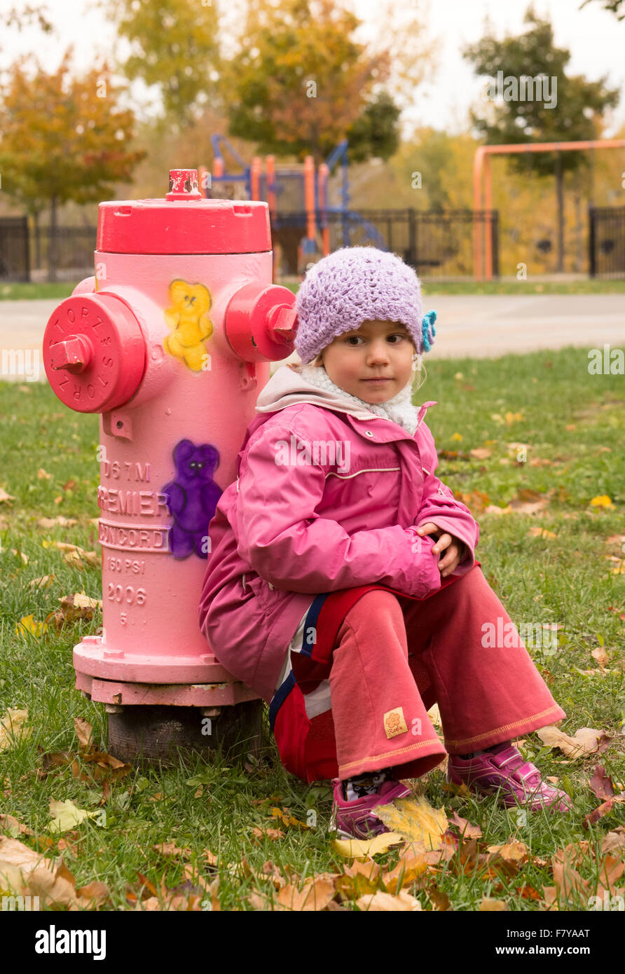 Child on a pink fire hydrant Stock Photo