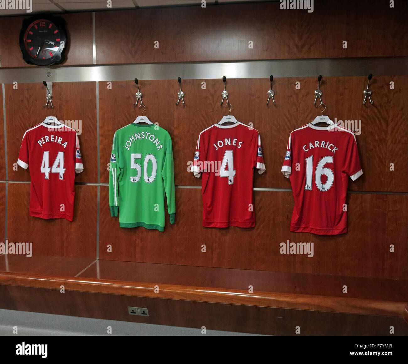 Mix of MUFC shirts hanging up in MUFC dressing room, with MUFC clock, Old Trafford, Manchester Stock Photo