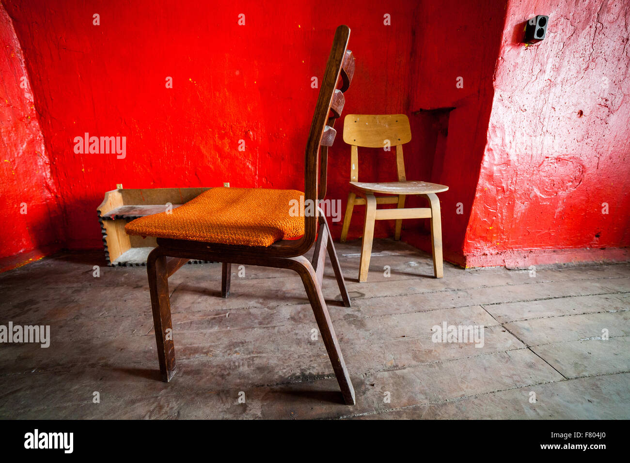 Abandoned prison in Tallinn - wooden chairs in red room Stock Photo