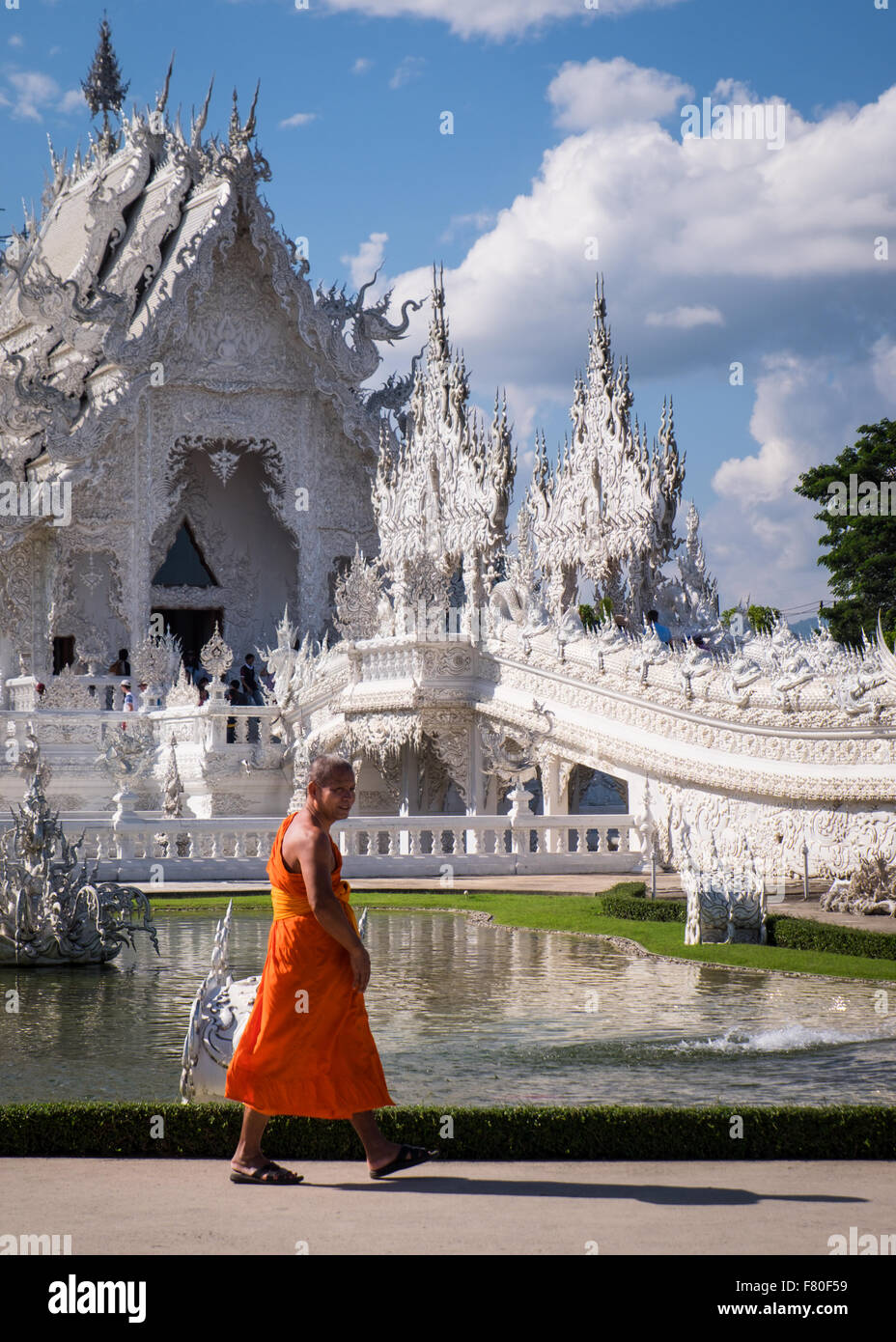 A monk walks past Wat Rong Khun, the 'white temple' outside of Chiang Rai in Northern Thailand. Stock Photo