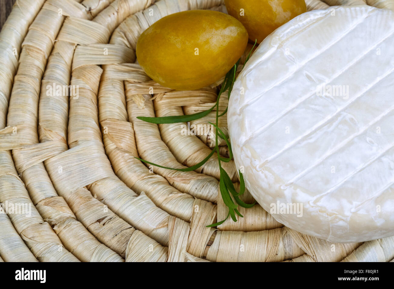 Round Brie cheese with yellow plums and estragon Stock Photo Alamy