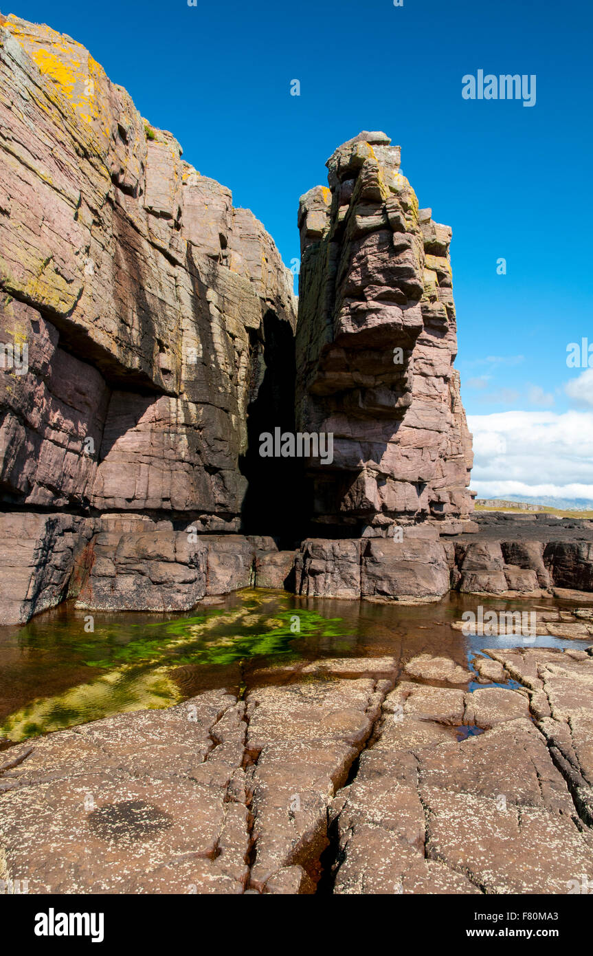 Rock formations in the cliffs of Torridonian red sandstone towering above a rock pool on the island of Handa, Sutherland, Scotla Stock Photo