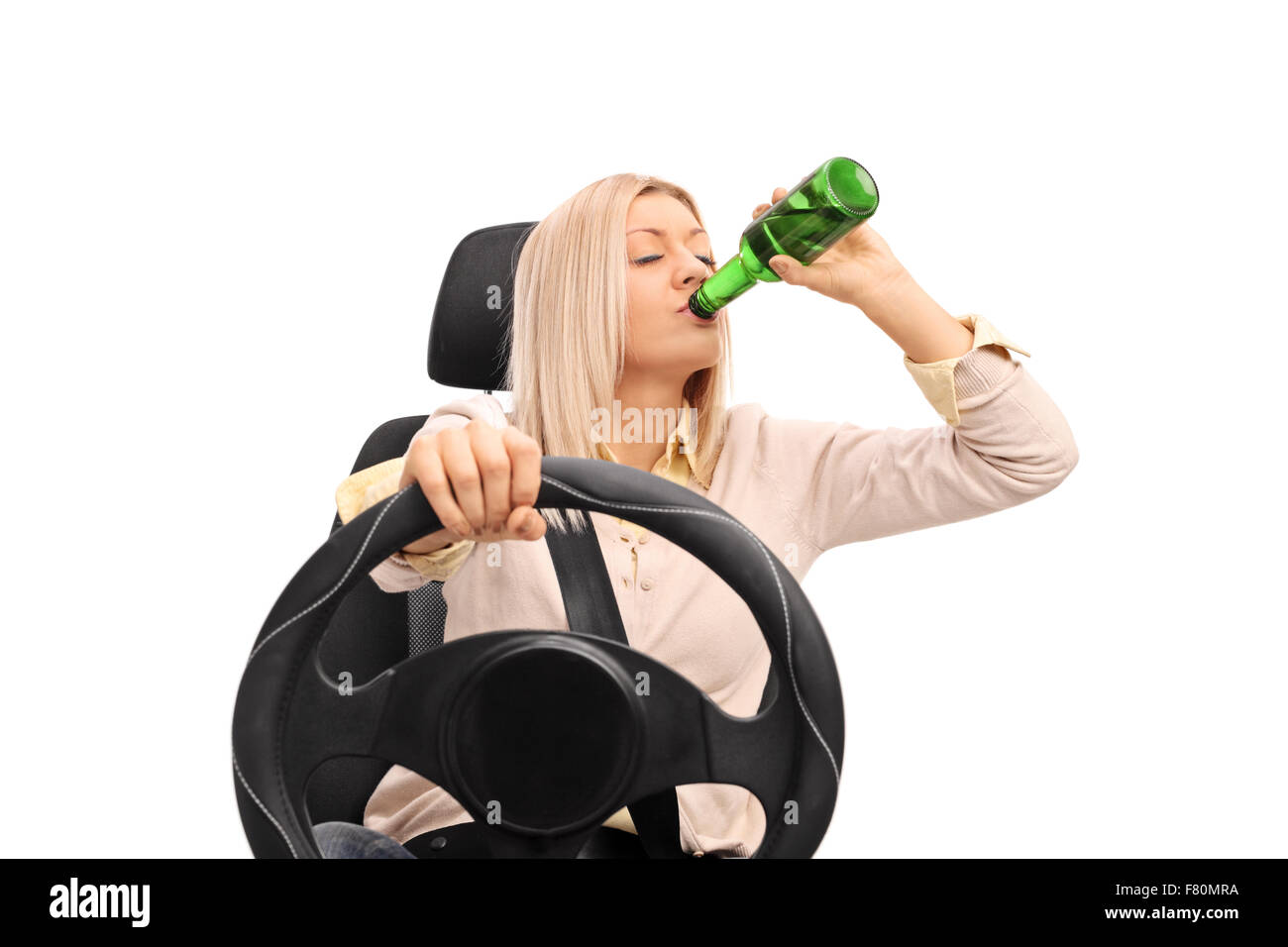 Studio shot of an irresponsible young woman drinking a beer and driving isolated on white background Stock Photo