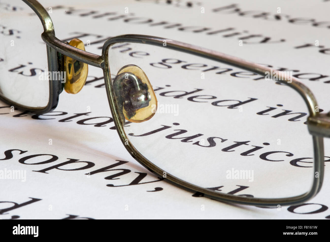Eye glasses leaned on a sheet, reading a text containing the word justice Stock Photo