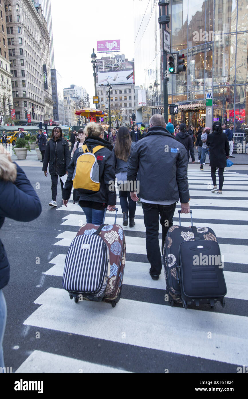 Visitors to New York City pull their luggage down Broadway at 34th