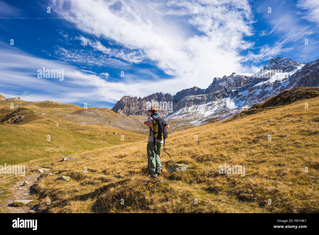 Hiker walking on a colorful valley with great panoramic view and autumnal vivid colors. Wide angle shot in the Italian French Al Stock Photo