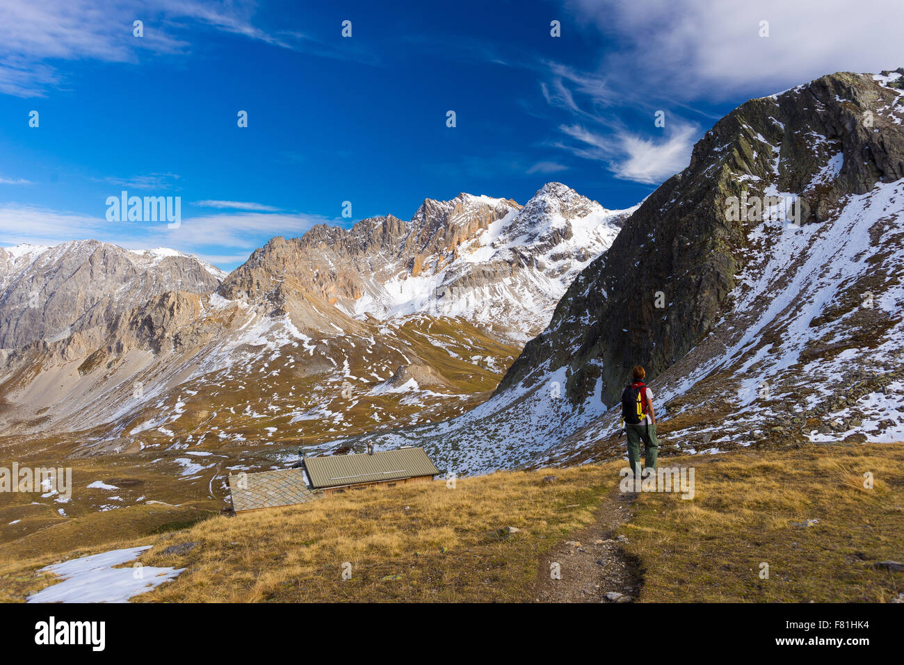 Hiker walking on a colorful valley with great panoramic view and autumnal vivid colors. Wide angle shot in the Italian French Al Stock Photo