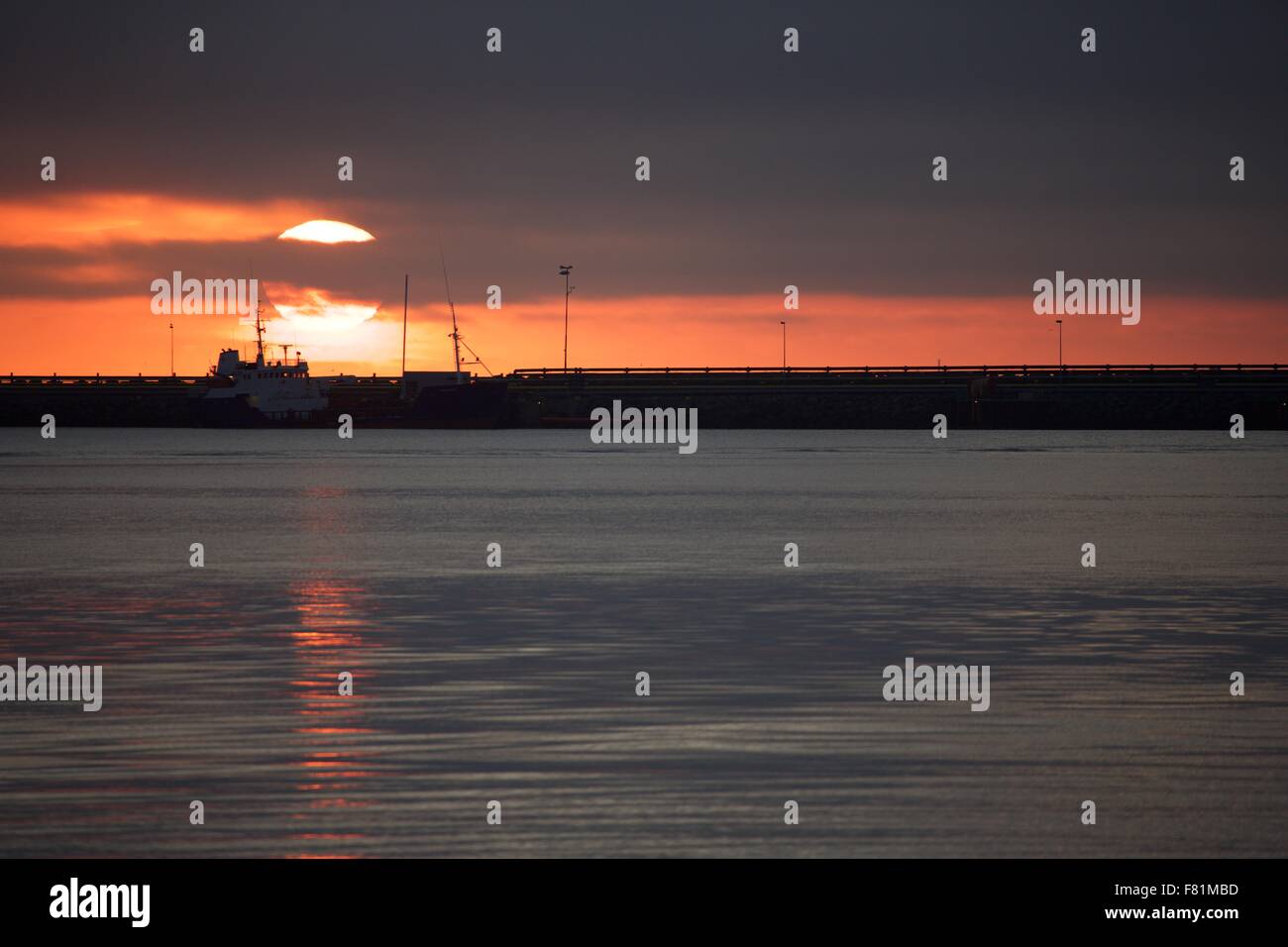 The midnight summer sun sets on the Summer Solstice over the harbor in Reykjavik, Iceland Stock Photo
