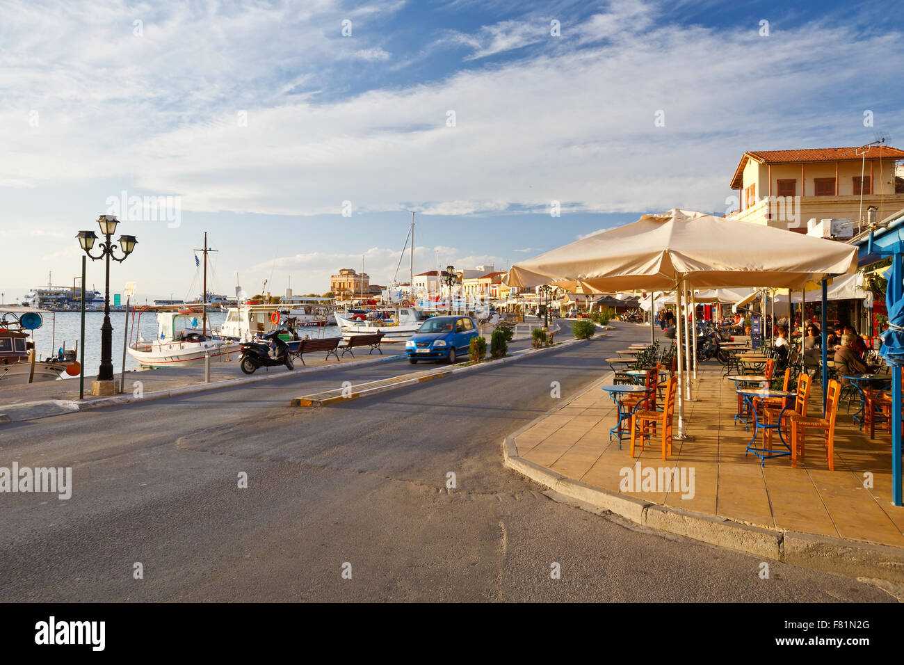 Street view of the coffee shops, bars and restaurants and the harbour of Aegina town, Greece Stock Photo
