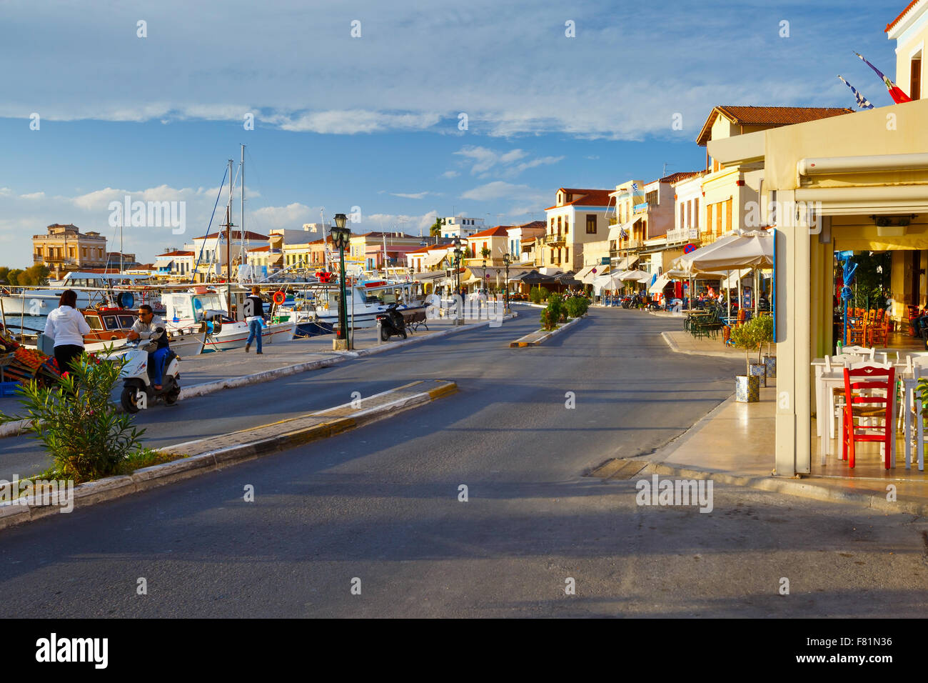 Street view of the coffee shops, bars and restaurants and the harbour of Aegina town, Greece Stock Photo