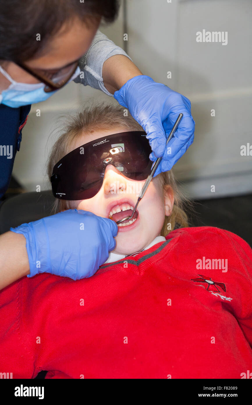Young girl 5 yr five year old child wearing protection glasses during check up @ childrens dentist / children's dental practice Stock Photo