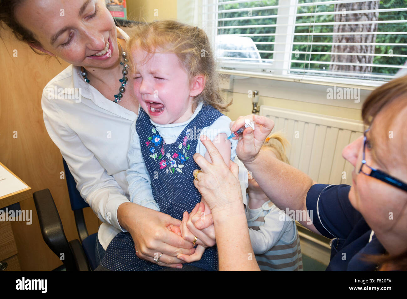 Nurse giving NHS 4-in-1 pre-school booster & MMR second dose immunisation /  inoculation / jab to a three 3 year old child / girl Stock Photo - Alamy